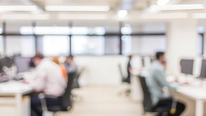 A trendy open office layout with blurred desks, computers, and team members collaborating in a modern workspace.