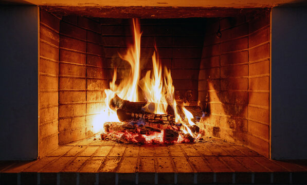 Fire burning in a fireplace, wood logs and flames. Warm home, heat. Christmas holiday