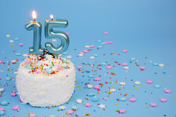 Coconut birthday cake with burning candles, anniversary 15 years and many colorful sprinkles on...