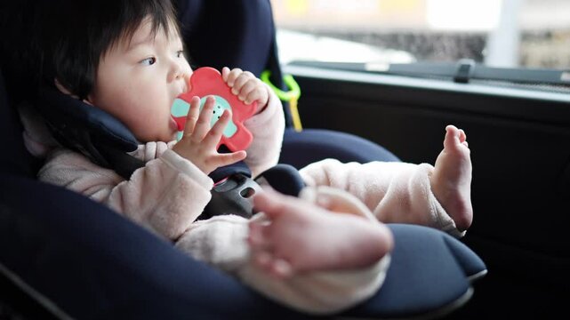 6-month-old Japanese baby girl is placed in baby seat in back seat of car.