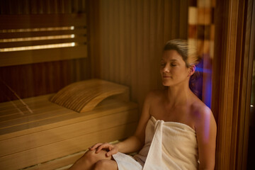 Relaxed woman sitting in sauna at spa.