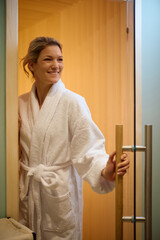 Happy woman in bathrobe entering in spa center.