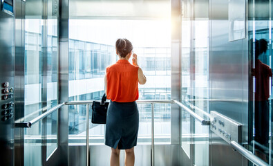 Businesswoman using mobile phone in the elevator