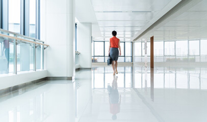 Fototapeta premium Back view of businesswoman walking on office corridor