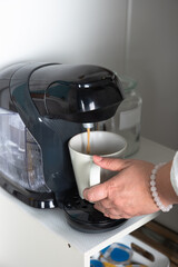 Close-up view  of a coffee pot and a woman's hand holding a white cup.  Coffee and home concept