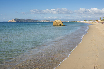 Poetto beach in Cagliari, with blue water and a characteristic rock in the sea