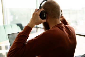 Close-up of man putting on wireless headphones while working or studying