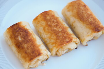 Savory crispy rolls, perfectly cooked and served on a plate, ideal for food photography and culinary themes.