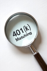 Close-up of magnifying glass highlighting the text '401(k) Matching', emphasizing financial savings and retirement planning.