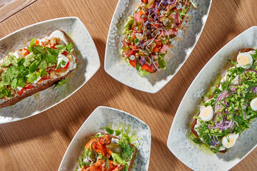 A delectable spread of four open-faced sandwiches, or smorrebrod, each with a unique and vibrant combination of toppings.