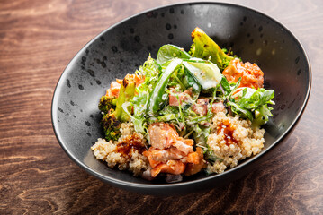 A vibrant bowl of quinoa topped with grilled salmon, fresh vegetables like broccoli and cucumber, drizzled with a savory sauce. Ideal for promoting healthy eating or gourmet cuisine.