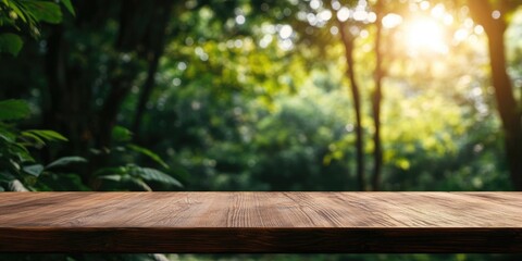 Fototapeta premium Wooden tabletop in the foreground with a blurred lush green background and soft golden sunlight filtering through trees creating a serene atmosphere
