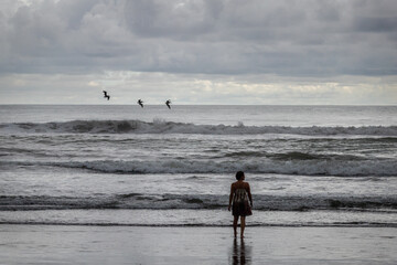 Femme devant le pacifique contemplatif avec oiseaux et vagues