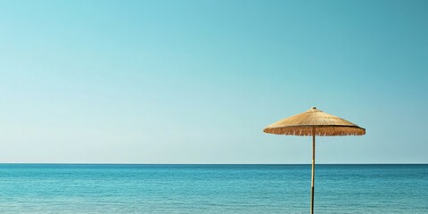 Serene beach scene featuring a straw umbrella on a wooden pole against a clear blue sky and calm turquoise ocean, ideal for summer vacation themes.