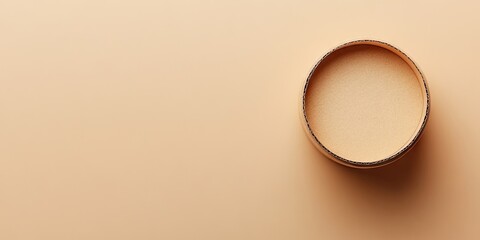 Top view of a circular empty cardboard gift box on a smooth beige surface with soft lighting highlighting its wooden texture and minimalist design