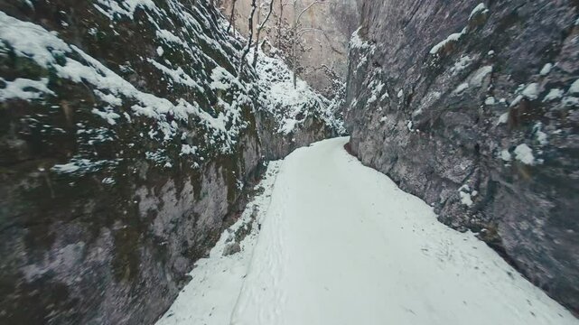 Drone flight through the stunning Zarnesti Gorges, showcasing snow-covered cliffs, sunlit forests, and the serene winter beauty of the Carpathian Mountains.