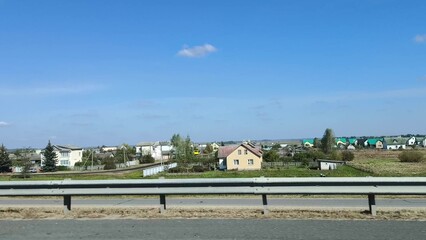 Obraz premium the car is in motion, the view from the window. Autumn landscape, road, residential buildings in rural areas, view from the car window