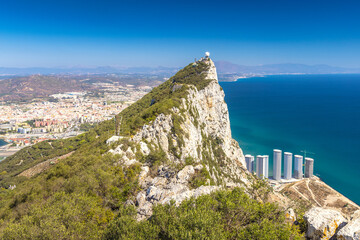 Naklejka premium Gibraltar, British Overseas Territory and city on the Iberian Peninsula. Coastal clifftop view with city and ocean. A panoramic vista of a dramatic coastline, showcasing a rocky cliff, city and sea.