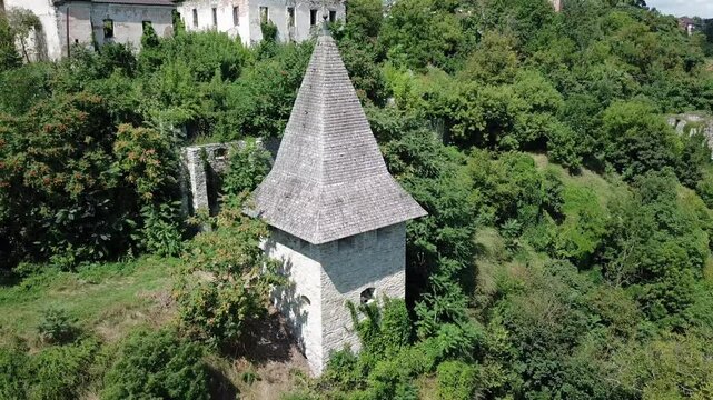 Aerial pan left towards Kushnirska Tower surrounded with greenery and old buildings at Kamianets Podilski,Ukraine.