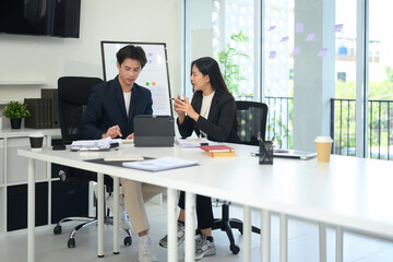 Fototapeta premium Two businesspeople dressed in formal suit working together on a project at bright office