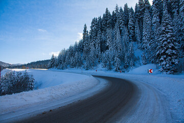 Snowy winter road in a mountain forest. A beautiful winter landscape.