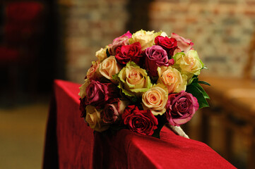 Vibrant roses in various colors arranged as a bouquet resting on a red cloth, perfect for weddings, celebrations, and romantic occasions.