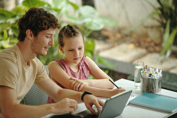 Dad helping his daughter to do homework online at home