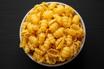 Homemade Dry Raw Gnocchi Pasta in a Bowl on a black background, top view. Flat lay, overhead, from above.