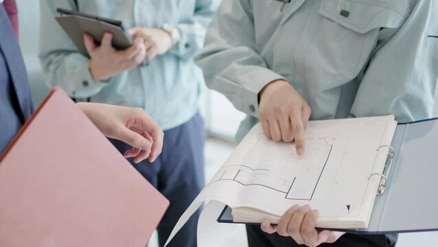 クライアントと打ち合わせをする作業服を着た男性