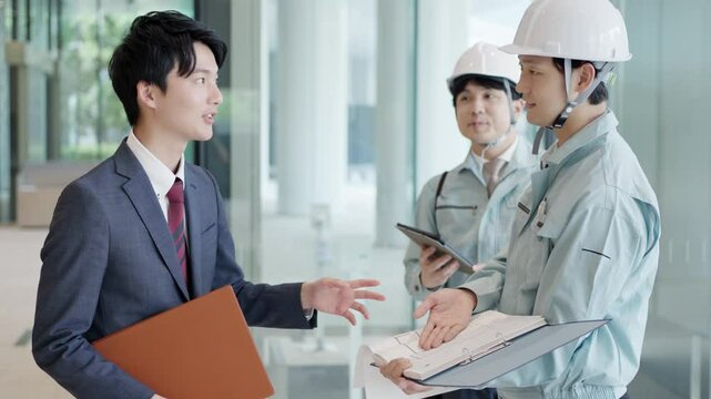 クライアントと打ち合わせをする作業服を着た男性