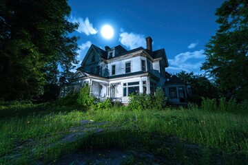 Obraz premium Eerie exploration of an abandoned victorian mansion with cracked windows and overgrown vines under a full moon mysterious shadows reveal hidden secrets