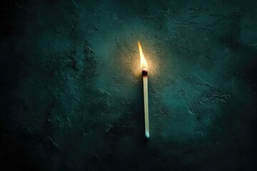 Burning matchstick on dark textured surface with abstract shadows