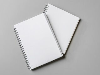 Elegant flat lay composition of two blank spiral-bound notebooks with a pencil on a minimalist grey background, showcasing the beauty and simplicity of stationery for note-taking or sketching
