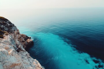 Turquoise coastal waters meeting rocky cliffs under clear sky