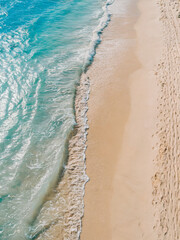 tropical holiday, vacance beach: A bright and vibrant top-down view of a sandy beach with gentle ocean waves meeting the shore in perfect horizontal alignment