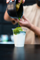Close up of a matcha latte being poured into a take away glass