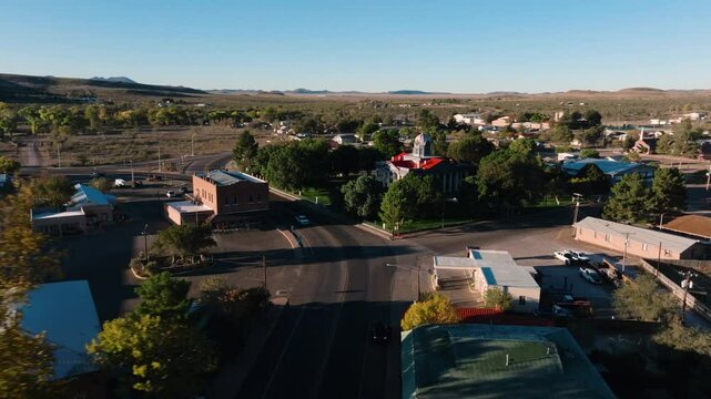 Orbiting city hadll in small rural Texas town at sunrise, single car drives on empty road, aerial 4k