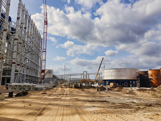 Construction site features towering cranes and expansive machinery under a dramatic sky in the heart of the city