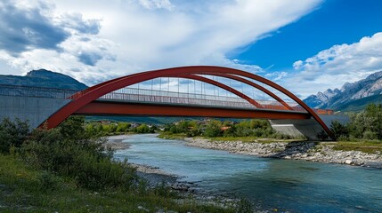 Obraz premium Red bridge spans river below mountains and cloudy sky.