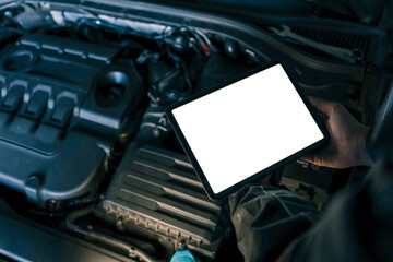 A tablet with a blank screen held by a mechanic above a car engine, symbolizing modern diagnostic tools for vehicle maintenance and repair. The engine is visible in the background