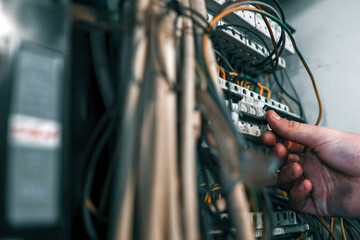 Electrician adjusting wiring in a circuit breaker panel. Concept of electrical maintenance, repair,...