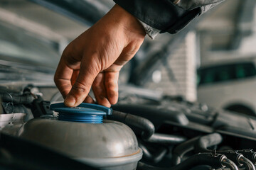 Mechanic tightening or loosening a blue cap on a vehicle's engine component during maintenance work...