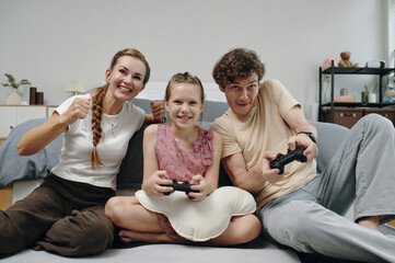 Happy family using joysticks to play video game together during leisure time at home