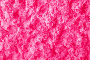Closeup view of a fluffy, deep pink fabric. The texture is dense and soft, resembling fur or a plush carpet. The fibers are long and create a visually appealing, shaggy surface.