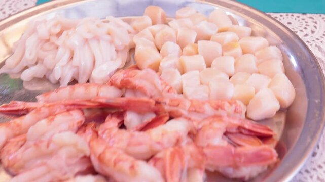 Scallops without shells, shrimp and squid on a plate, cooking seafood