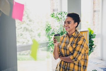 Photo of pretty young girl drink coffee paper cup wear yellow plaid shirt coworking successful nice light office
