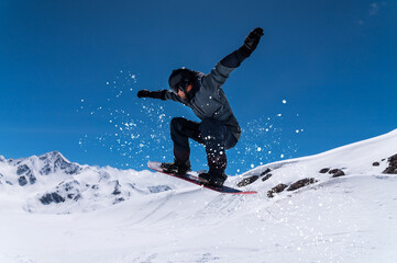 Fototapeta premium Flying snowboarder in the mountains, extreme sport. Wide angle on the flight in the jump of the snowboarder