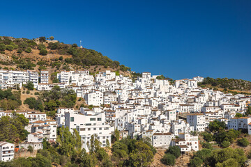 Fototapeta premium Casares town in Andalusia, Spain, Europe. Whitewashed village nestled on a hillside, bathed in sunlight against a clear blue sky. A picturesque and charming scene.