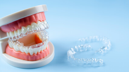 Invisible dental teeth brackets tooth aligners on blue background. Plastic braces dentistry retainers to straighten teeth