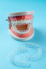 Close-up. Transparent aligners for artificial jaw teeth on a blue background